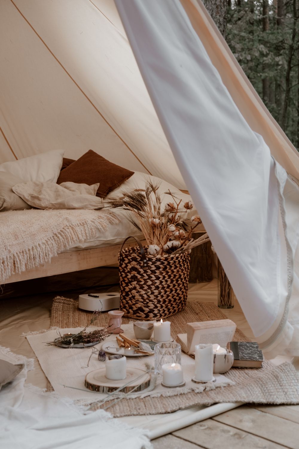Inside the tent: a linen-dressed bed, woven basket and dried grasses
